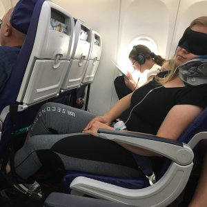 sleeping on an airplane with Trtl pillow, foot hammock, eye ask, headphones